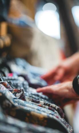 Sifting through clothes on a rack.