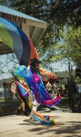 Masked dancer dressed in the rainbow dancing.