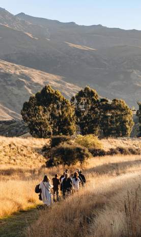 A group of people walking though a big field with mountains in the background