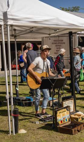 A man playing a guitar under a tent at a market.