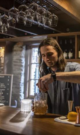 Bartender mixing a cocktail at The Blue Door bar in Arrowtown.