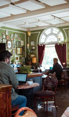 Inside of a cafe with people working on their laptops and ordering food.