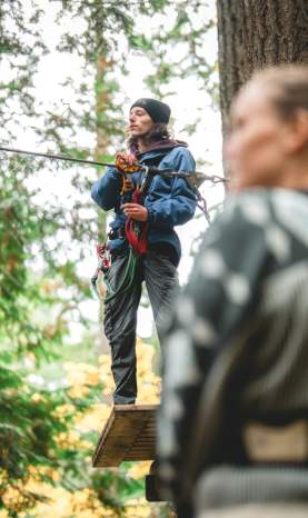 A person getting ready to show two others how to safely use the zipline