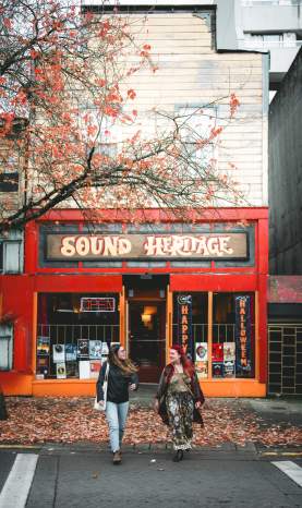 Two people walking outside of Sound Heritage on Victoria Crescent