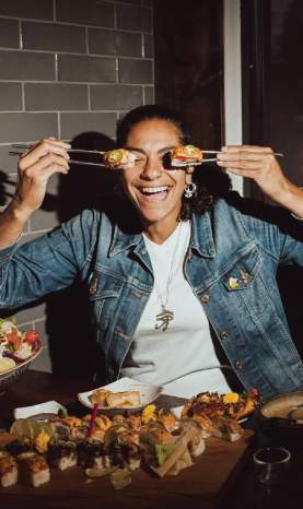 A person using chopsticks to hold sushi up to their eyes.