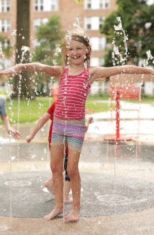 A young girl and boy play in fountains of water at the Thompson Park Splash Pad in Overland Park, KS