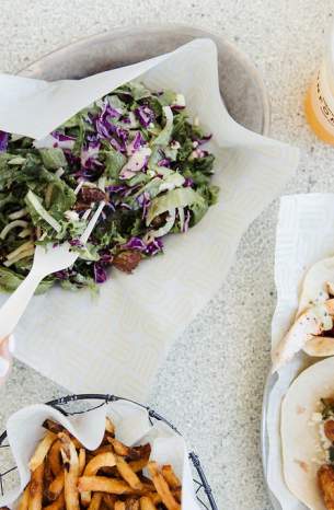 Person using fork to eat a salad, tacos and fries at Unforked