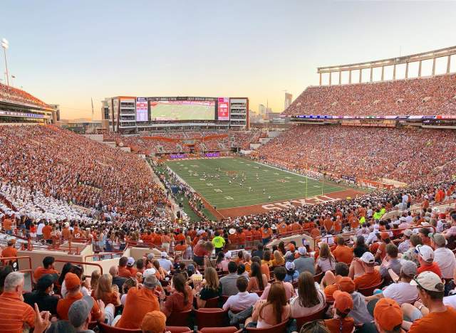 Fans in burnt orange, white and grey filling the seats at DKR Stadium at the University of Texas at Austin.