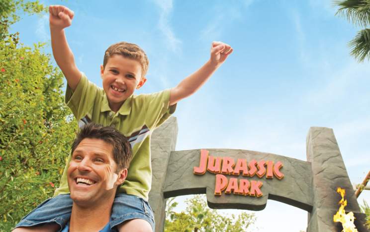 Universal's Islands of Adventure father and son posing in front of the Jurassic Park sign