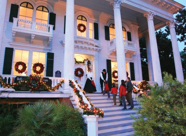 Family walking up the Bellamy Mansion entrance stairs during Christmas