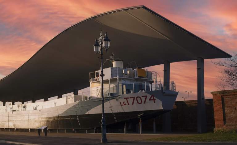 Photograph of LCT 7074 outside The D-Day Story, under a vibrant pink sky