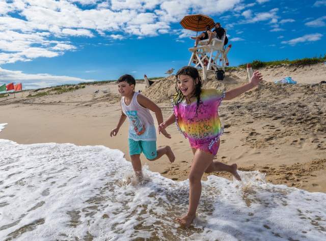 A boy and a girl run into the surf on the beach at Hither Hills State Park