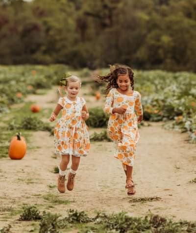Two girls skipping through a pumpkin patch