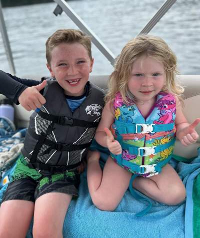 two children in life jackets give a thumbs up while in a boat on Raystown Lake