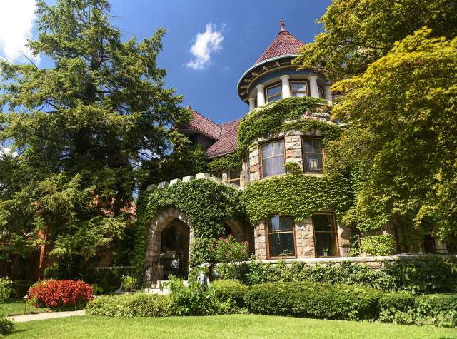 exterior of a cobblestone house covered in ivy with a yard with grass in front