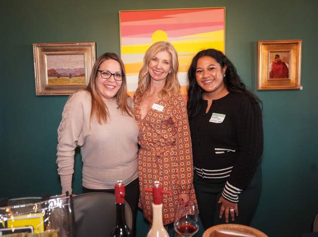 Three women standing close together and smiling