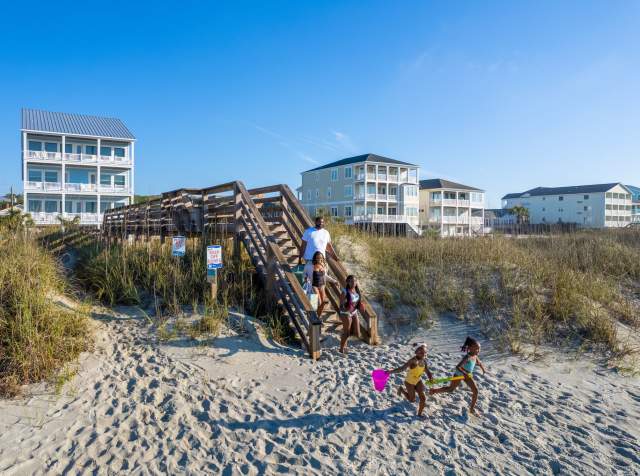 A family walking to the beach over the dunes