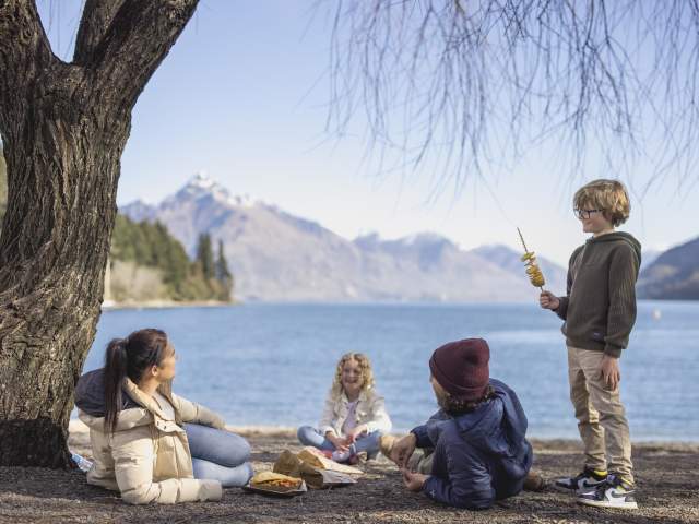 Family eating fish and chips at Queenstown Bay beach