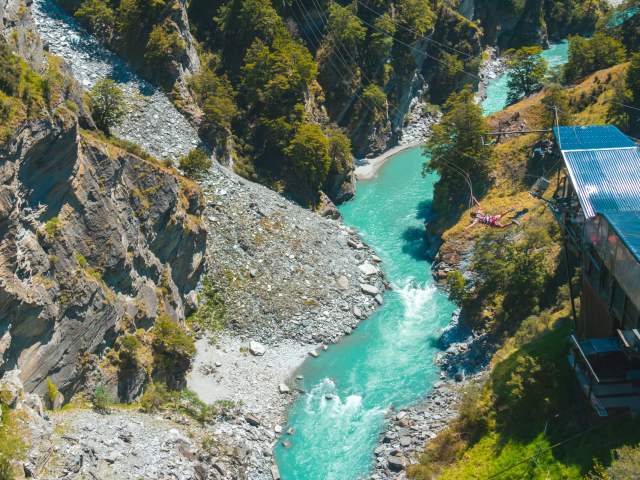 Far shot of a person doing the Canyon Swing with a river below