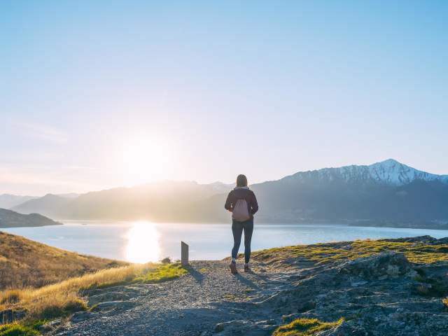 Person on trail at sunset with lake and mountain views