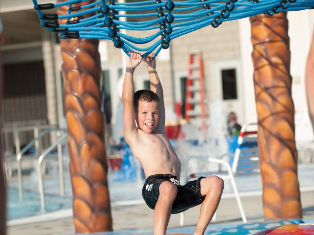 Kid swinging along the floating path at Freedom Springs Greenwood Aquatics Park in Johnson County