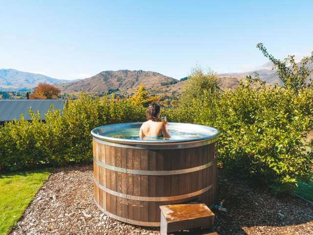 Women in wooden hot up looking at mountain view in a private backyard