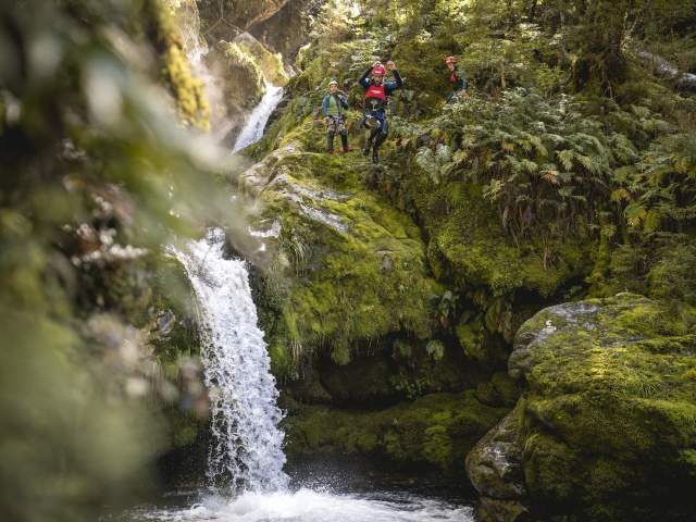 Person canyoning, jumping off a waterfall into a natural spring