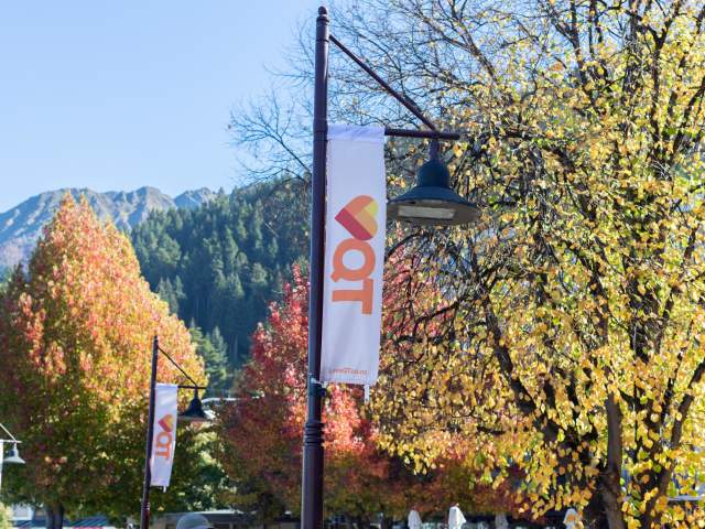 Love Queenstown flags displayed in the street with autumn trees and mountain in the background