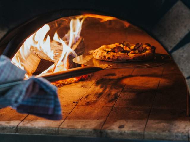 Pizza going into a wood fired oven