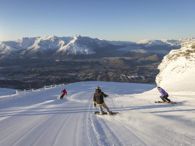 Snowboarders and skiers riding down snowy mountain