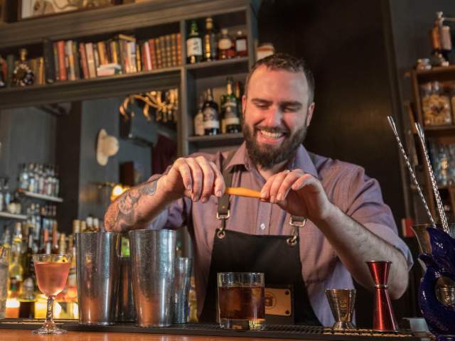 A barman preparing a cocktail at The Milk Thistle bar in Bristol - credit Paul Box