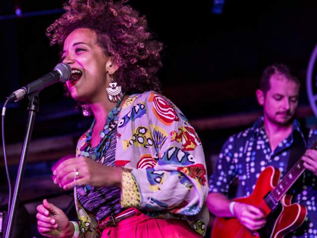 KP & The Boom Boom singer on stage with a guitarist playing behind her