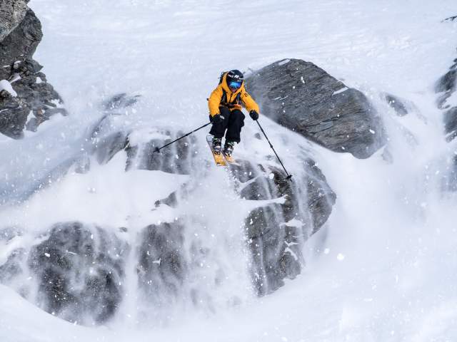 Freeskier Pete Oswald skiing down a rocky mountain face