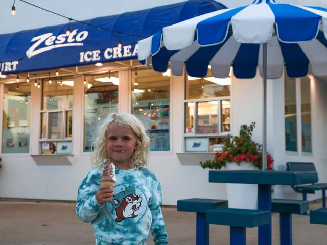 A girl eating ice cream in front of Zesto Ice Cream parlor in steuben county,