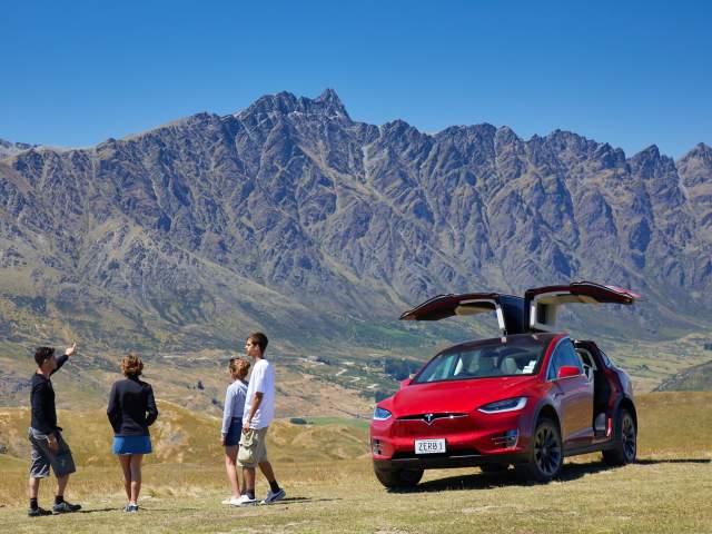 Family on Nomad Safari's Tesla Scenic Tour in front of the Remarkables mountains