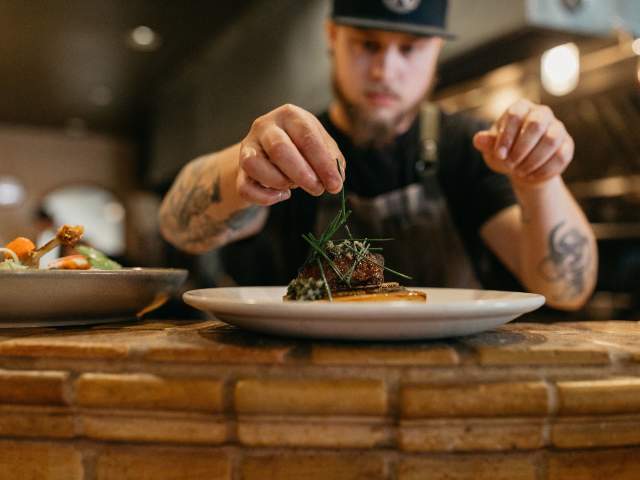 Chef puts finishing garnishes on a dish at Marche.