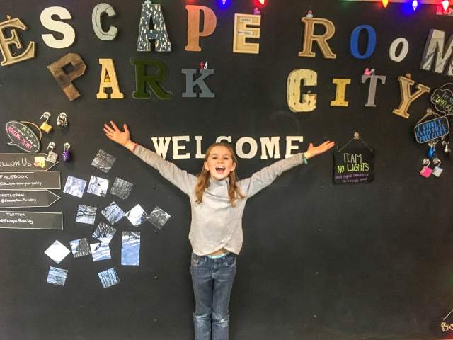 Girl stands in front of a sign that reads escape room
