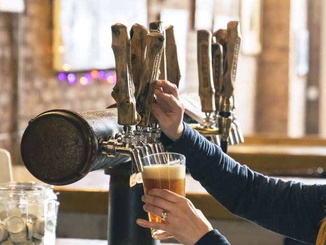 a bartender pulls the tap, pouring a fresh pint of beer