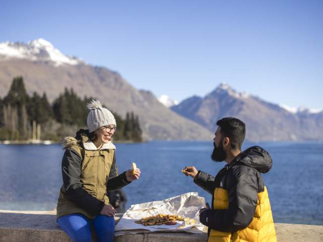 People eating Erik's Fish & Chips with lake and mountains in the background