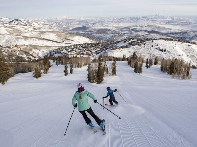 Mom and child skiing down a groomed trail