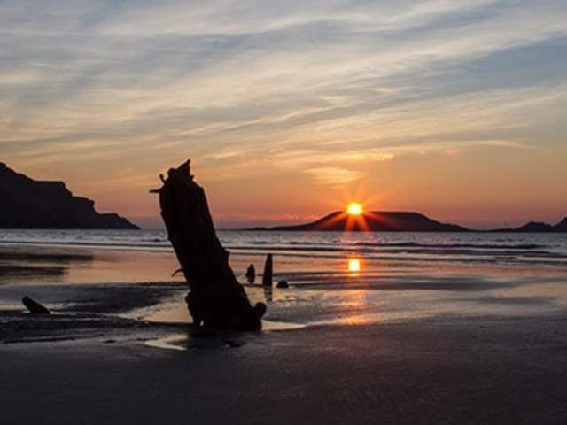 view of the helvetia shipwreck in rhossili against the sunset