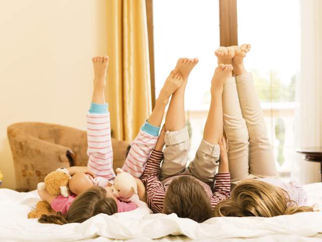 Children lying down on a bed with legs in the air