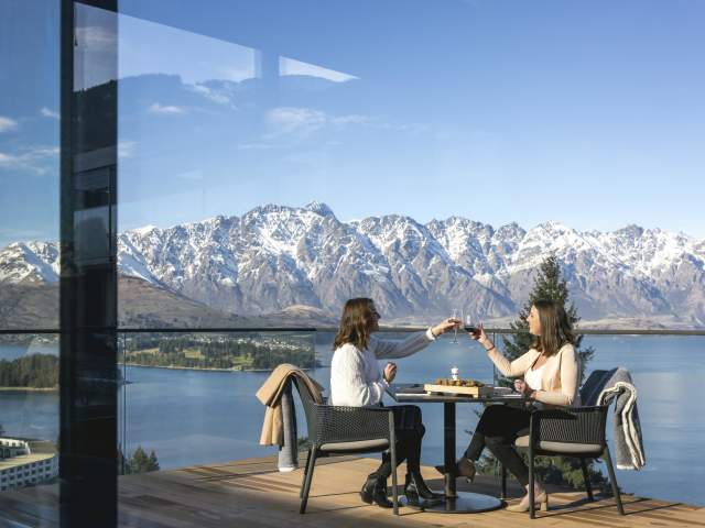 People dining outside with snow capped mountains in the background