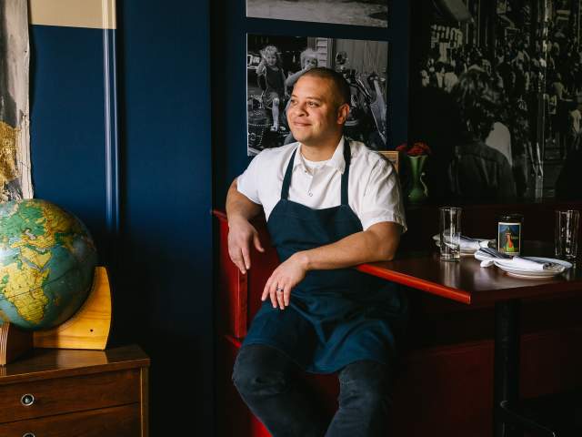 a chef sitting on a chair at a dining table in a restaurant