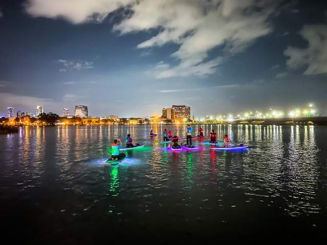 Paddleboarding at night near city with Epic Paddle Adventures