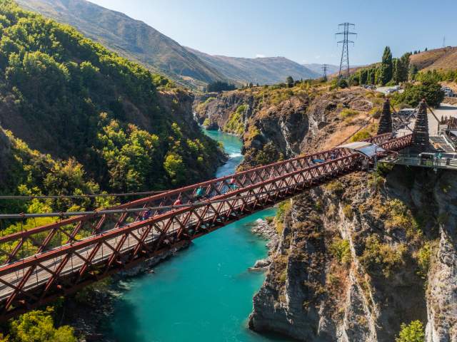 People biking over a bridge with vibrant blue water below