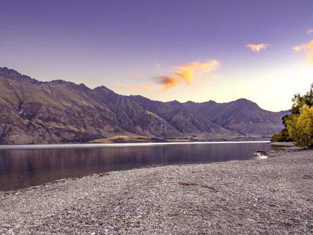 Scenic photo of lake and mountains taken at sunset.