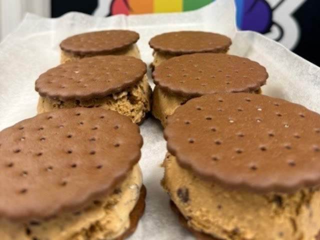 Six chocolate ice cream sandwiches on a serving dish in front of a sign that reads Ellwood