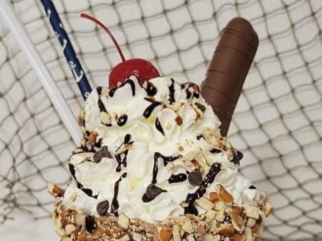 A loaded milkshake complete with whipped cream, a chocolate straw, chocolate syrup, and a cherry on top