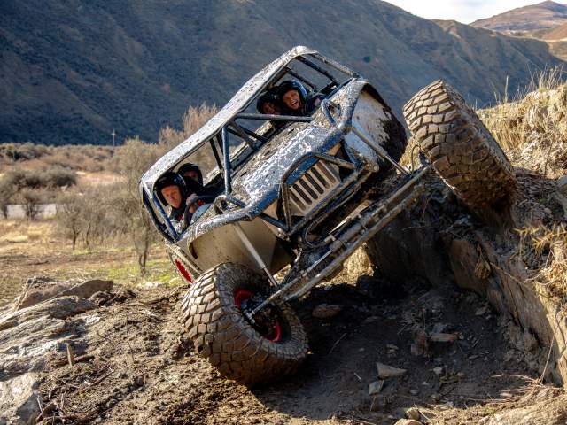 Group of people on uneven terrain in an Oxbow off-roader vehicle
